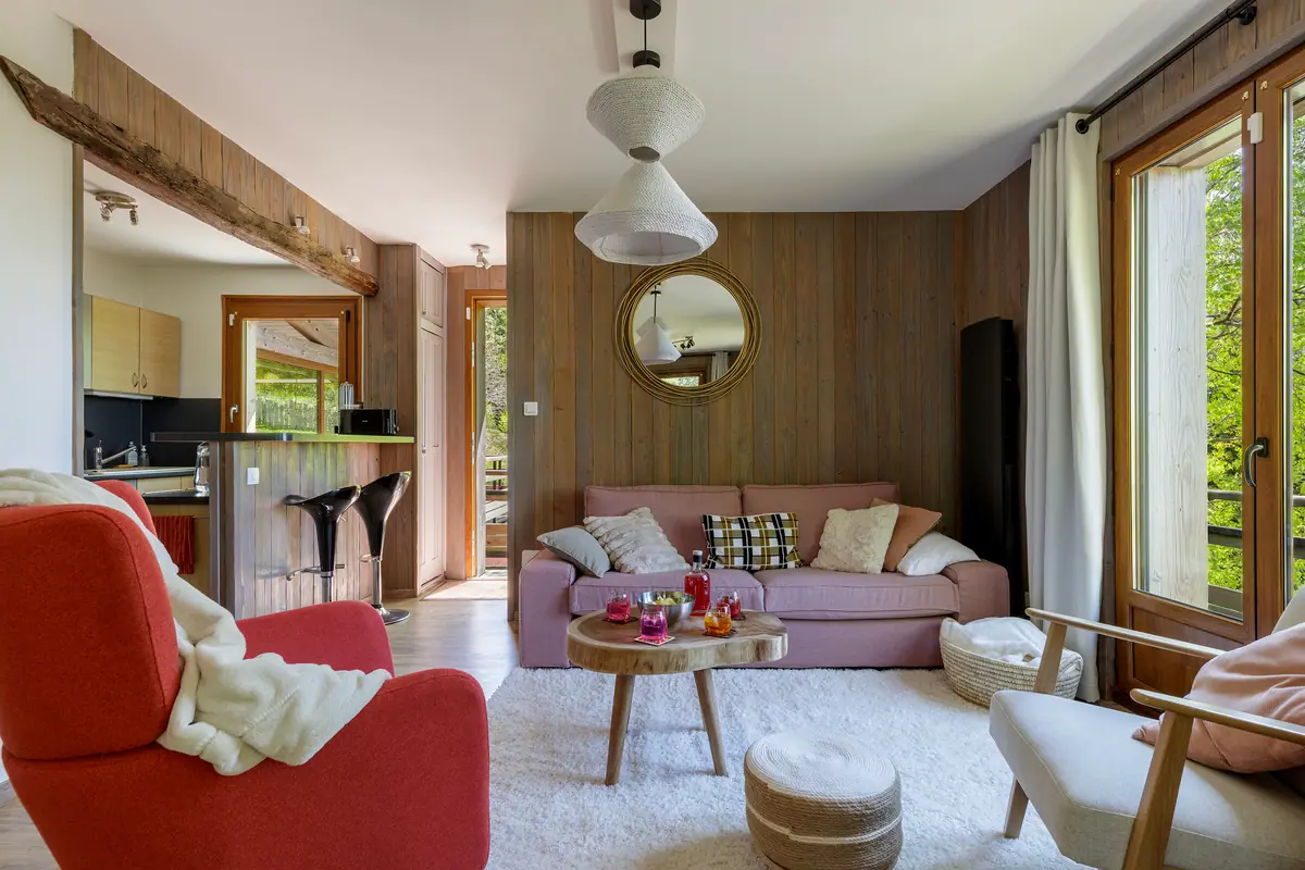 Salon du chalet avec fauteuils corail et canapé, accès balcon