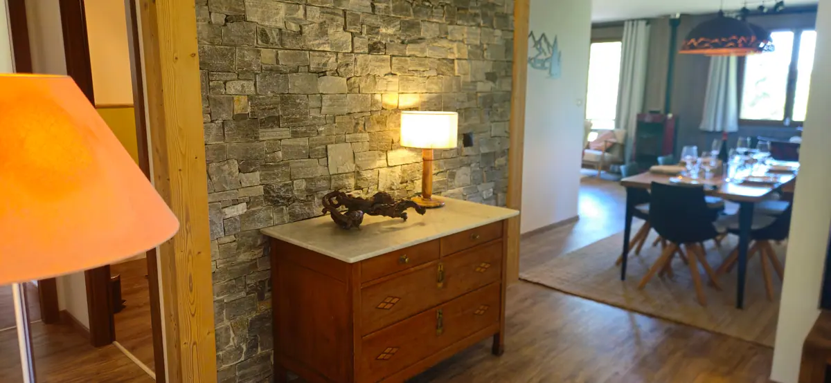 Entrée du chalet, mur de pierre et commode ancienne